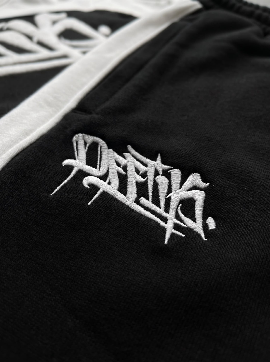 Black jacket with white embroidered logo on a black background, image 3