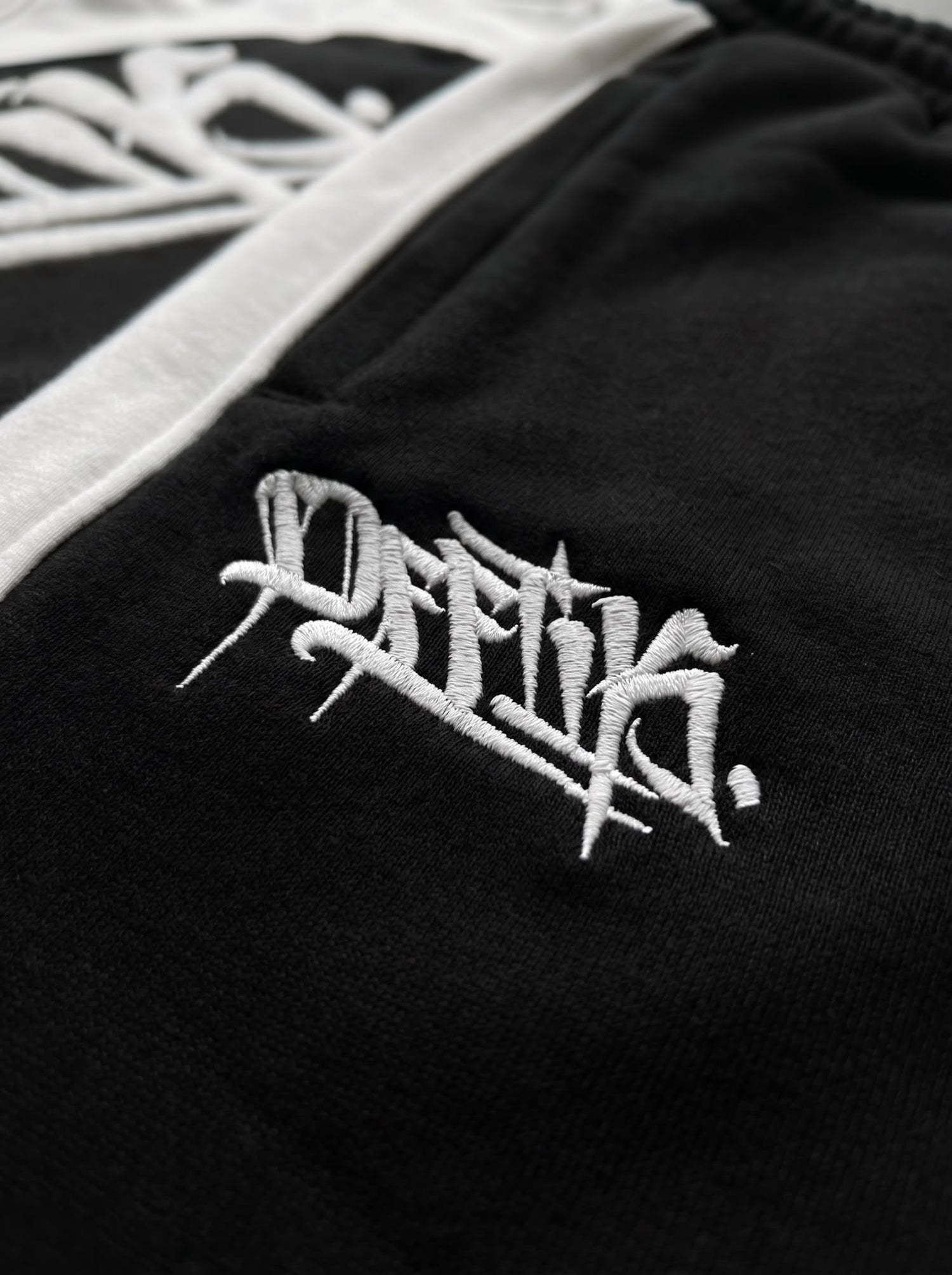 Black jacket with white embroidered logo on a black background