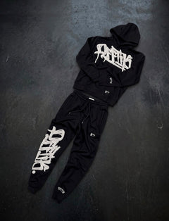Black hoodie and pants set with white branding on a dark surface