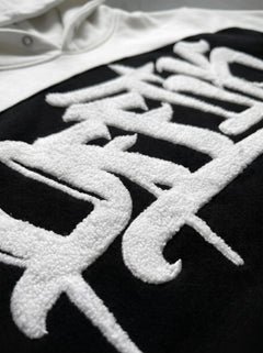 Black shirt with white embroidered design on a plain background