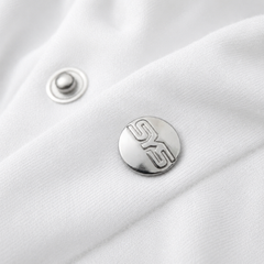 Close-up of a silver button with a logo on a white fabric background