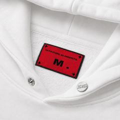 Close-up of a white shirt with a red label featuring text and a logo.