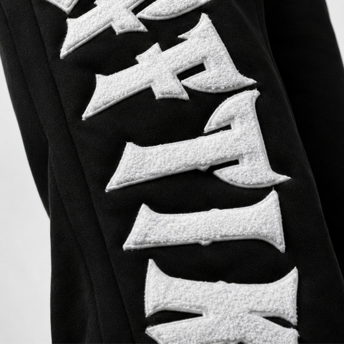 Black garment with white textured letters on a light gray background, image 4