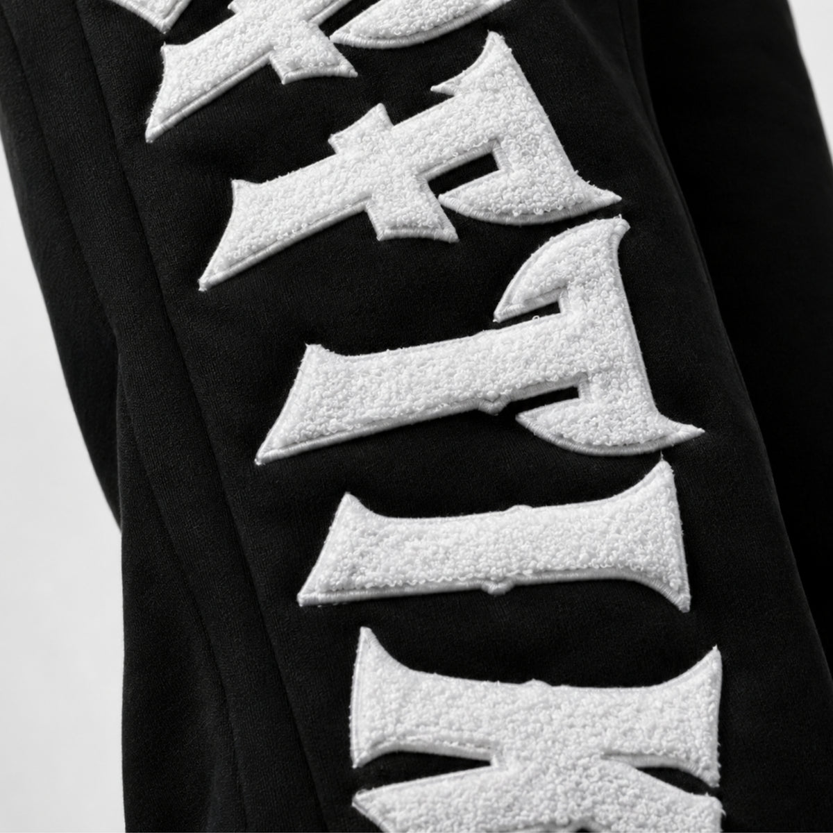 Black garment with white textured letters on a light gray background, image 4