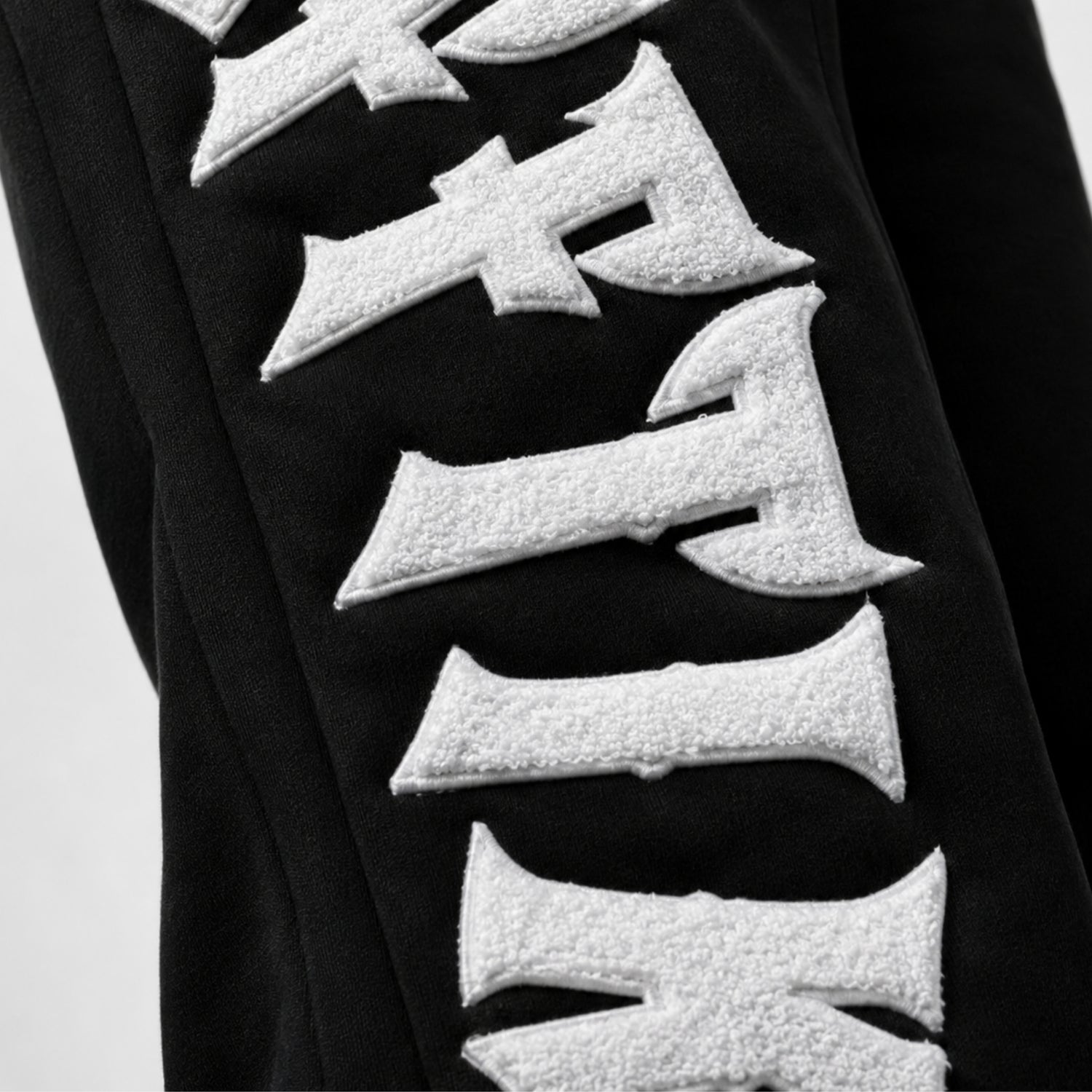 Black garment with white textured letters on a light gray background