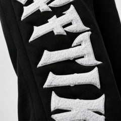 Black garment with white textured letters on a light gray background