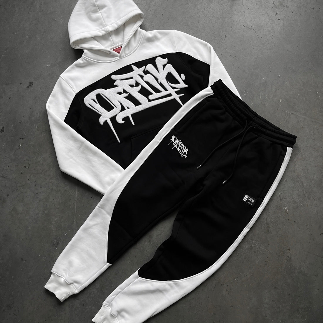 White and black hoodie with graphic design on a gray surface, image 8