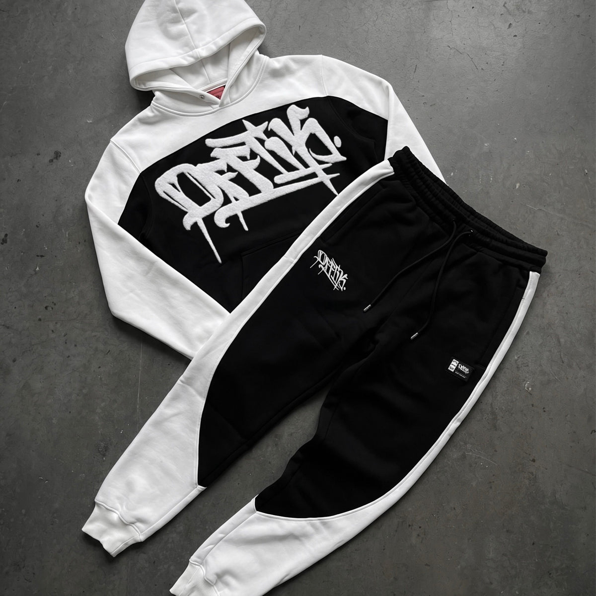 White and black hoodie with graphic design on a gray surface, image 8