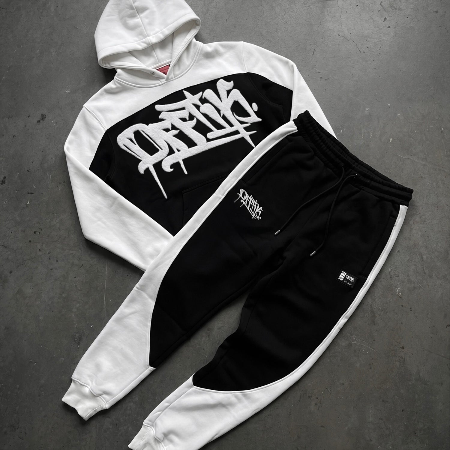 White and black hoodie with graphic design on a gray surface
