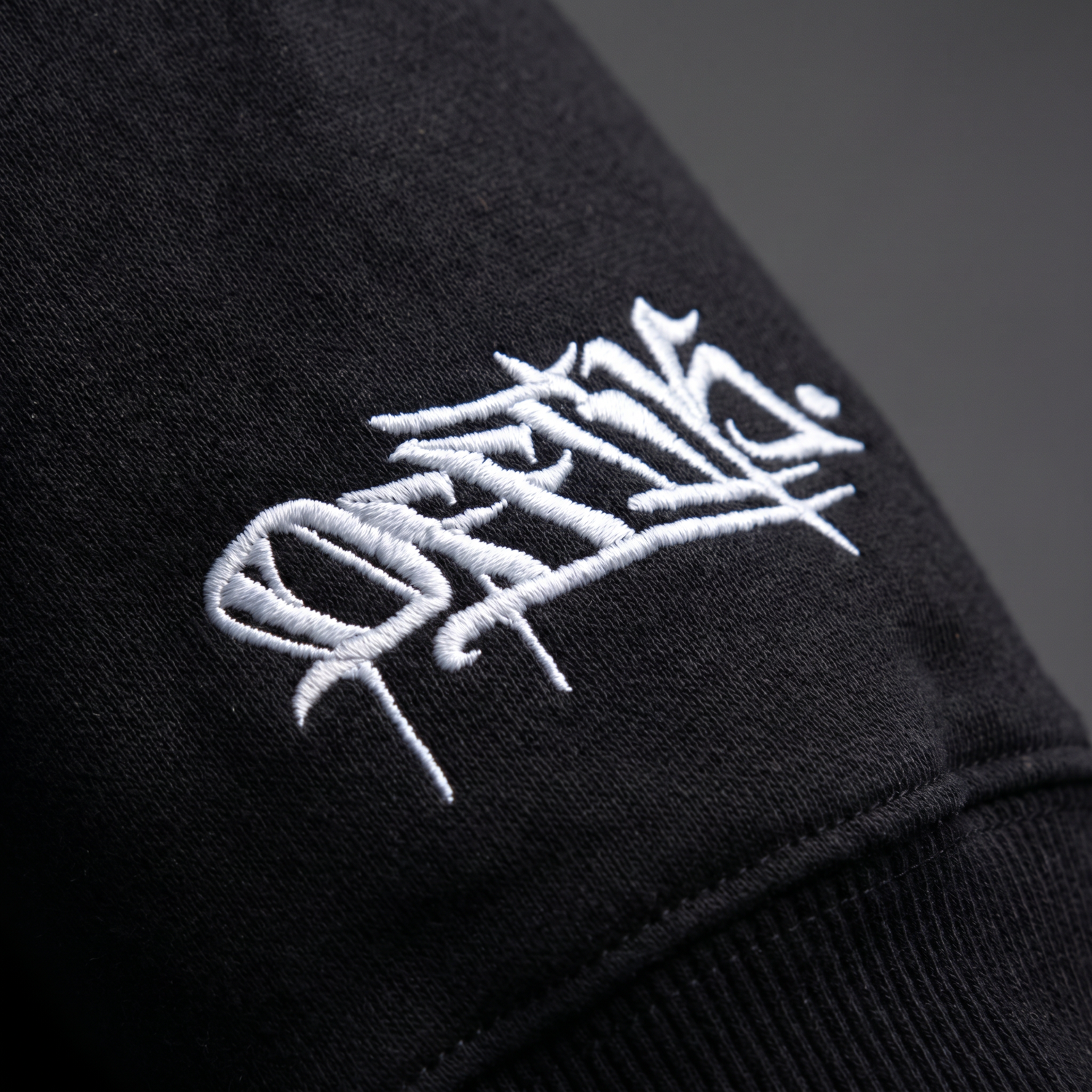 white embroidered logo on a dark background